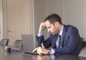 Worried businessman holding his head in his office